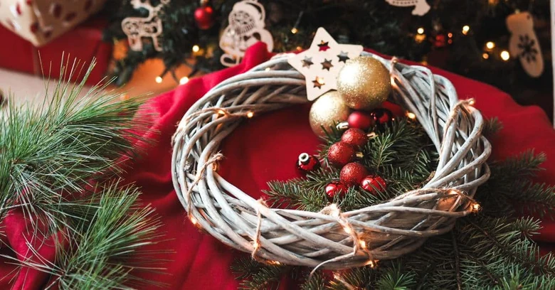 Hotový adventní věnec s borovicemi a dekoracemi na červeném podkladu